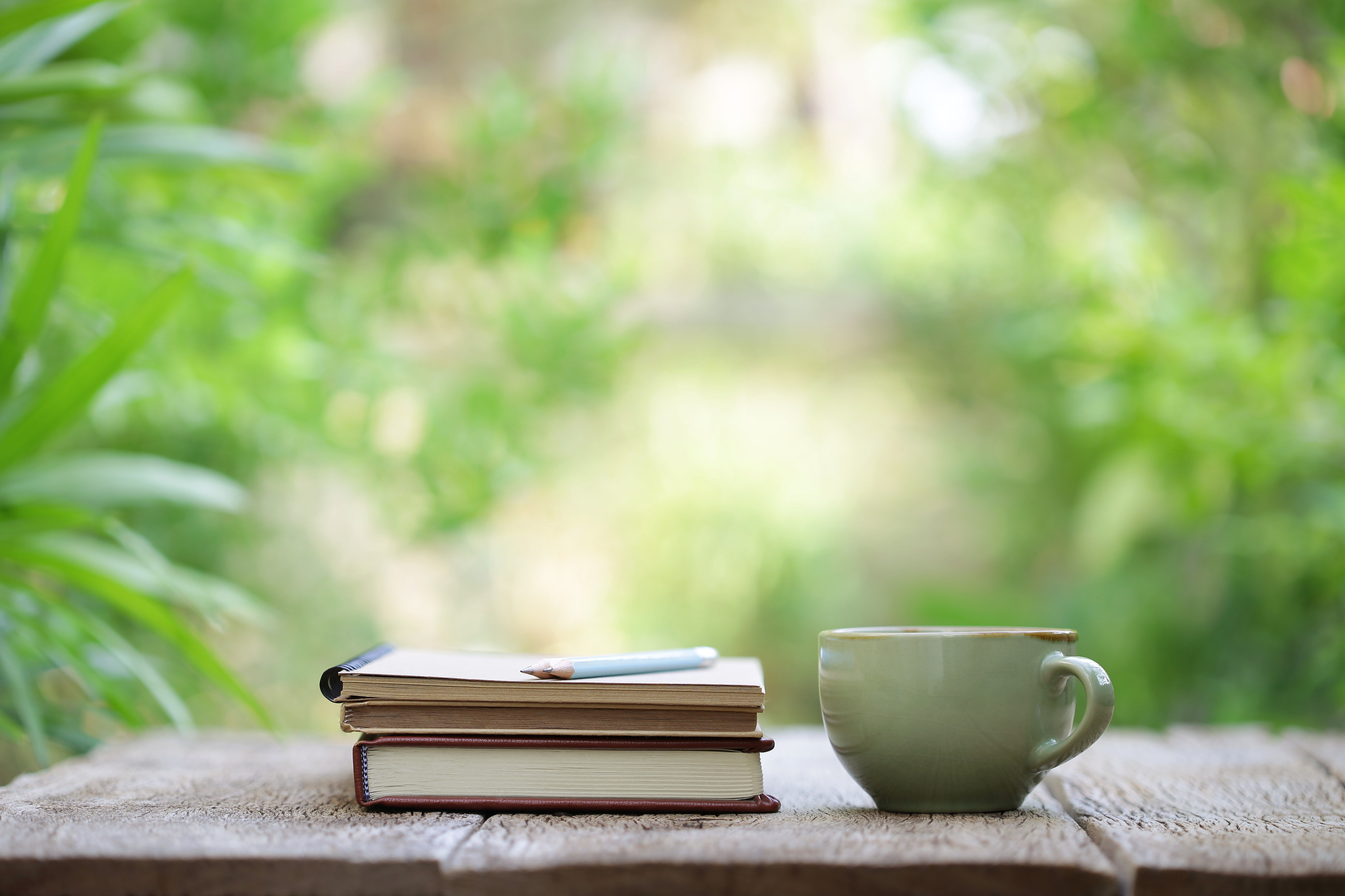 Notebook with pencil and cup on wooden table