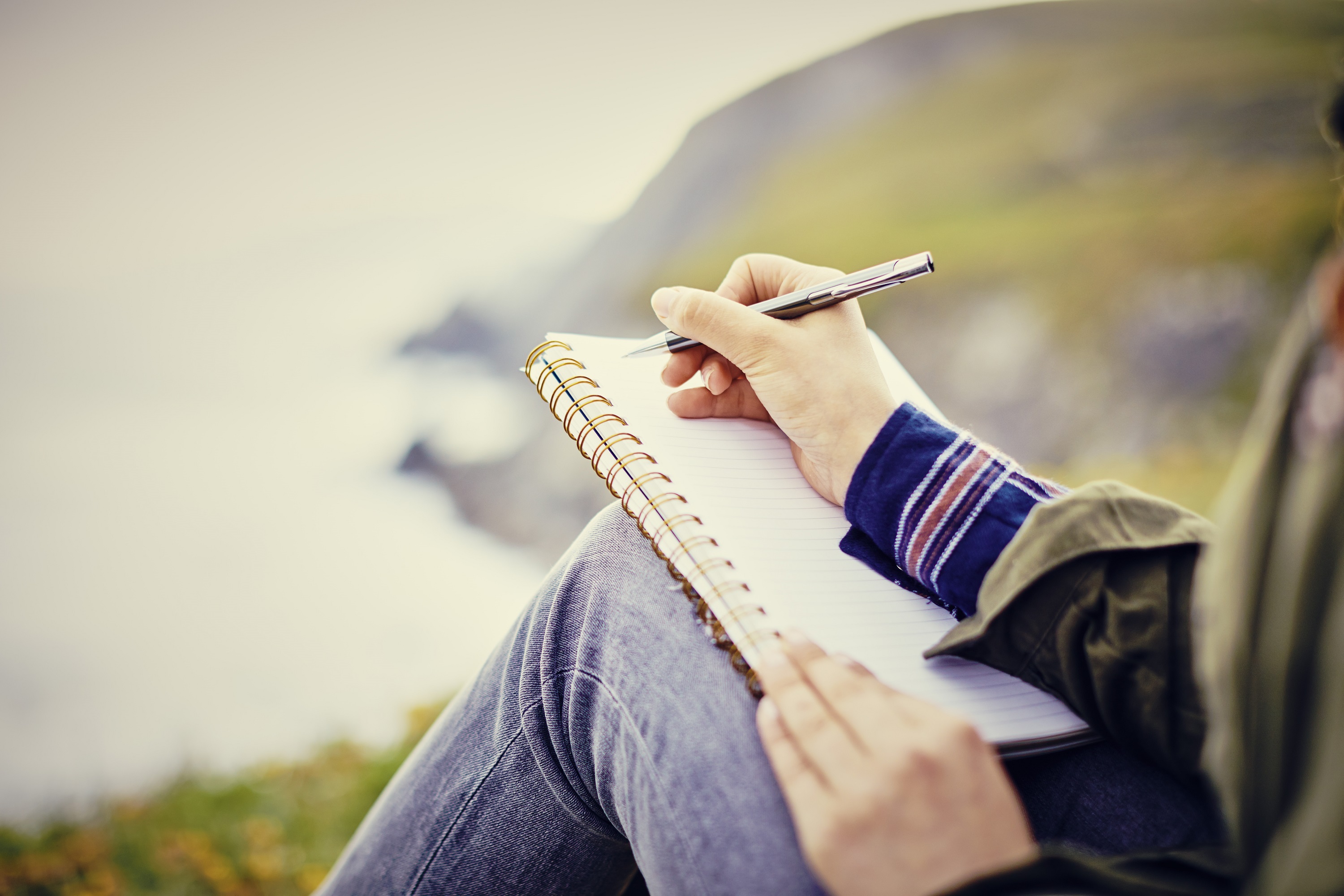 Close-up of a woman writing in a notebook on hillside