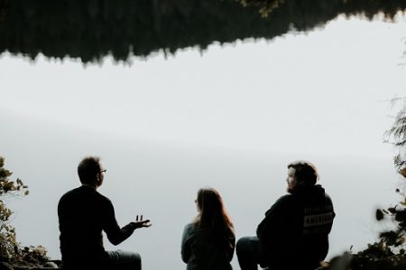 Image of three people having a conversation, looking out over a misty hillside