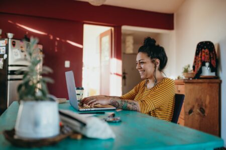Millennial tattooed freelancer Latina woman working on her laptop at home